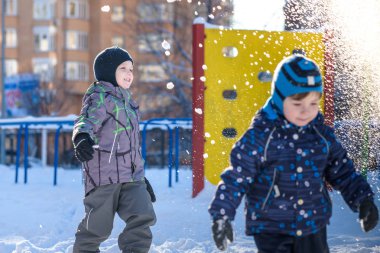 İki küçük çocuklar renkli giysiler açık havada kar yağışı sırasında oynayan çocuk. Kışın soğuk günlerinde çocuklu etkin boş. Mutlu kardeşler ve eğleniyor İkizler kar