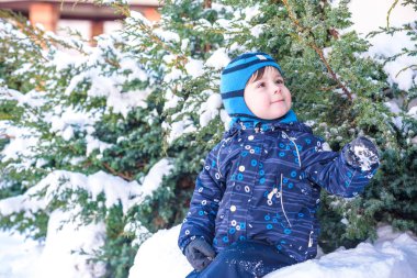 Komik küçük çocuk çocuk renkli giysiler açık havada kar yağışı sırasında oynamaya. Kışın soğuk karlı günlerde çocuklu etkin boş. Mutlu çocuk eğlenceli ve kar