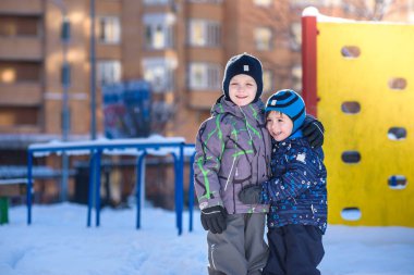İki küçük çocuklar renkli giysiler açık havada kar yağışı sırasında oynayan çocuk. Kışın soğuk günlerinde çocuklu etkin boş. Mutlu kardeşler ve eğleniyor İkizler kar