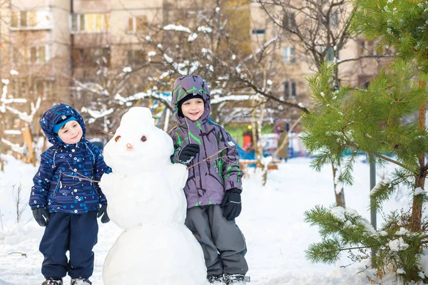 2 つの小さな兄弟の子供男の子雪だるまを作って、遊んで、寒い日に屋外雪で楽しい時を過します。冬のアクティブ レジャー子供. — ストック写真