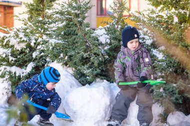 İki küçük çocuklar renkli giysiler açık havada kar yağışı sırasında oynayan çocuk. Kışın soğuk günlerinde çocuklu etkin boş. Mutlu kardeşler ve eğleniyor İkizler kar