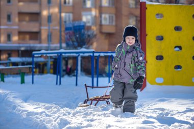 Açık havada kış şehirde yürüyüş çocuk mutlu onun kızak sürükler. Çocuk gülen ve having fun.