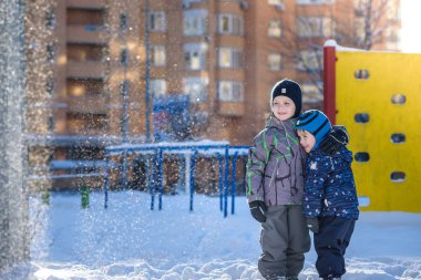 İki küçük çocuklar renkli giysiler açık havada kar yağışı sırasında oynayan çocuk. Kışın soğuk günlerinde çocuklu etkin boş. Mutlu kardeşler ve eğleniyor İkizler kar