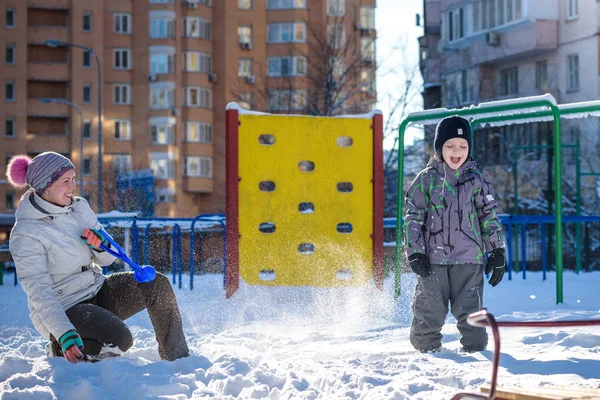 Mère et son fils profitent d'une belle journée d'hiver en plein air, jouant avec la neige en ville — Photo