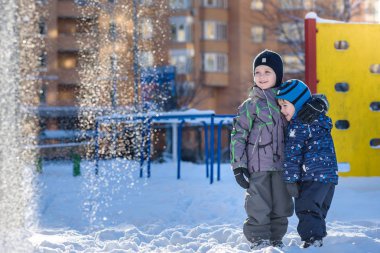 İki küçük çocuklar renkli giysiler açık havada kar yağışı sırasında oynayan çocuk. Kışın soğuk günlerinde çocuklu etkin boş. Mutlu kardeşler ve eğleniyor İkizler kar