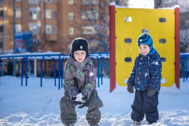 İki küçük çocuklar renkli giysiler açık havada kar yağışı sırasında oynayan çocuk. Kışın soğuk günlerinde çocuklu etkin boş. Mutlu kardeşler ve eğleniyor İkizler kar