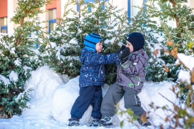 İki küçük çocuklar renkli giysiler açık havada kar yağışı sırasında oynayan çocuk. Kışın soğuk günlerinde çocuklu etkin boş. Mutlu kardeşler ve eğleniyor İkizler kar