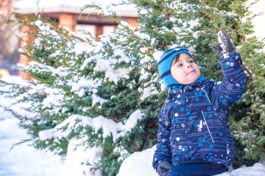 Komik küçük çocuk çocuk renkli giysiler açık havada kar yağışı sırasında oynamaya. Kışın soğuk karlı günlerde çocuklu etkin boş. Mutlu çocuk eğlenceli ve kar