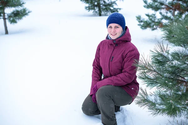 Bella donna che soffia nella neve in una pineta — Foto Stock
