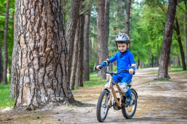Sevimli sarışın çocuk mutlu çocuk eğleniyor ilk bisikletini güneşli yaz günü, açık havada. Spor yapma çocuk. Çocuklar için etkin boş. kask giymek. gülümseyen ve cicling
