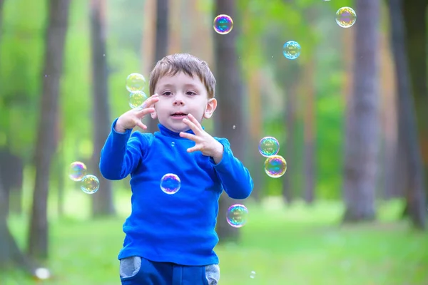 Menino com bolhas de sabão no parque de verão . — Fotografia de Stock