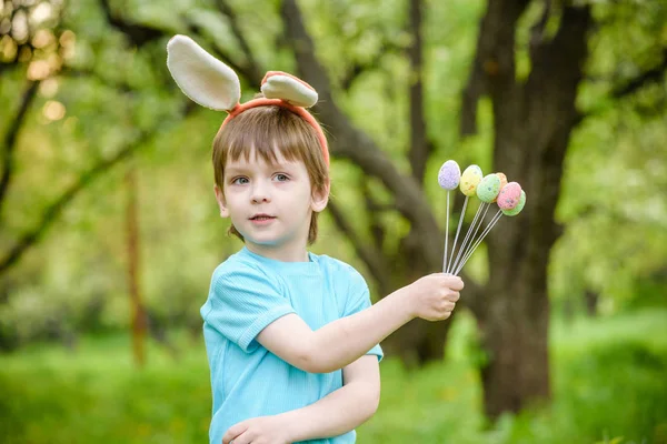 Malý chlapec loví velikonoční vajíčka na jarní zahradě ve dne. Roztomilý — Stock fotografie