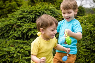 Paskalya yumurtası avındaki çocuklar bahar bahçesinde. Çocuklar yanar