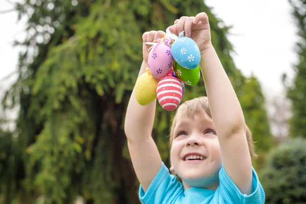 Huevos de Pascua de diferentes colores en las manos de un niño- caza de huevos —  Fotos de Stock