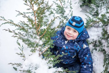 Çocuk çocuk açık havada kar yağışı sırasında renkli giysiler içinde kış portresi. Soğuk karlı günlerde çocukları ile etkin boş. Mutlu çocuk eğleniyor kar