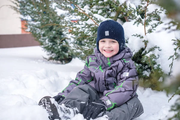 Retrato de invierno de niño con ropa colorida, al aire libre durante las nevadas. Ocio activo con los niños en los días nevados fríos. Niño feliz teniendo nieve divertida —  Fotos de Stock