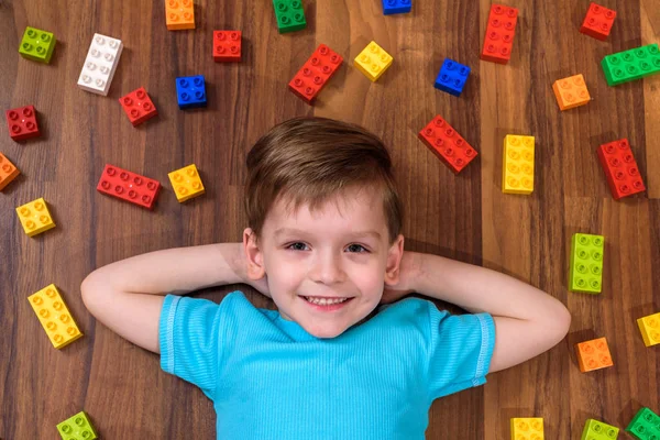 Pequeño niño caucásico jugando con un montón de bloques de plástico de colores — Foto de Stock