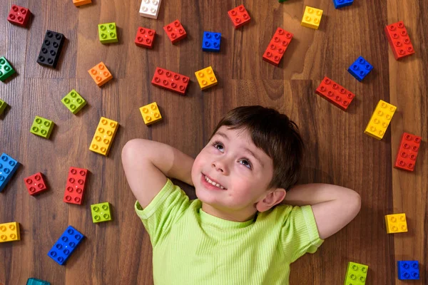 Pequeño niño caucásico jugando con un montón de bloques de plástico de colores — Foto de Stock