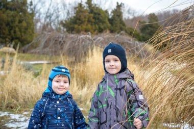 İki küçük çocuk çocuklar, el ele tutuşarak ve sarılma arkadaşlar. Çok güzel kardeş parlak renkli giysiler içinde. Mutlu çocuklar açık havada, kış veya sonbahar