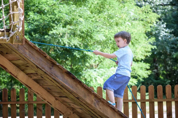 Pequeno menino criança garoto se divertindo em um parque infantil de madeira ao ar livre — Fotografia de Stock