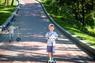 İki sevimli çocuklar, rekabet scooter, park, açık sürme yaz.