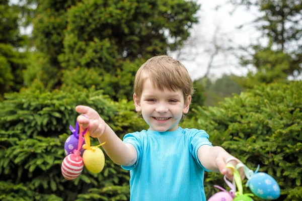 Oeufs de Pâques de différentes couleurs dans les mains d'un enfant- chasse aux œufs — Photo