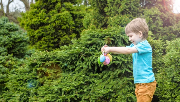 Kids on Easter egg hunt in blooming spring garden. Children searching for colorful eggs in flower meadow. Toddler boy and his brother friend kid play outdoors — Stock Photo, Image