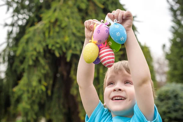 Huevos de Pascua de diferentes colores en las manos de un niño- caza de huevos —  Fotos de Stock