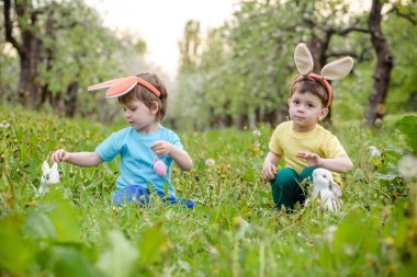 İki küçük çocuk Paskalya tavşanı kulağı takmış bahar bahçesinde, açık havada yumurta avına çıkmış. Kardeşler renkli yumurta bulmaktan zevk alıyor. Eski Hıristiyan katologu geleneği