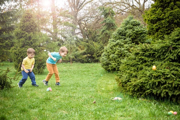 Los niños en la búsqueda de huevos de Pascua en el floreciente jardín de primavera. Niños sear — Foto de Stock