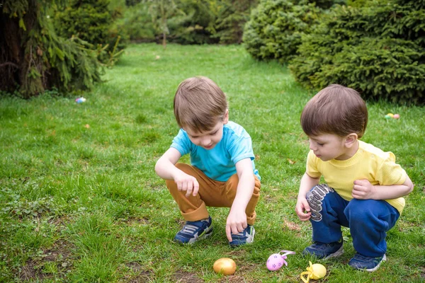 Los niños en la búsqueda de huevos de Pascua en el floreciente jardín de primavera. Niños sear — Foto de Stock