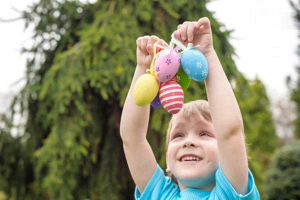 Huevos de Pascua de diferentes colores en las manos de un niño- caza de huevos —  Fotos de Stock