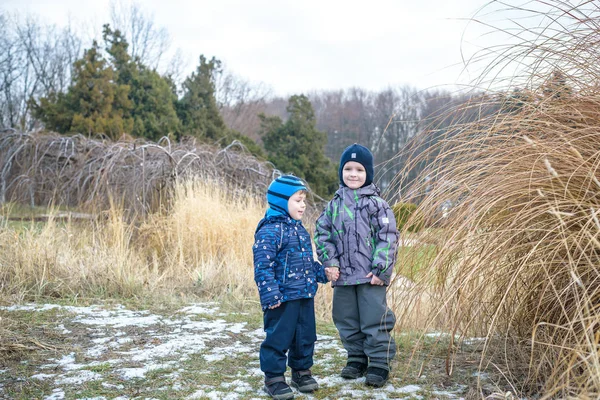 İki küçük çocuk çocuklar, el ele tutuşarak ve sarılma arkadaşlar. Çok güzel kardeş parlak renkli giysiler içinde. Mutlu çocuklar açık havada, kış veya sonbahar