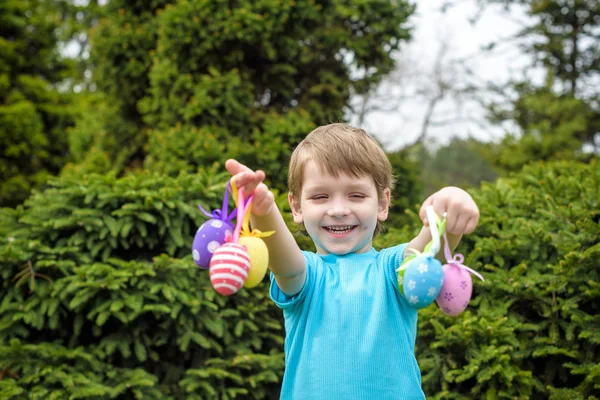 Huevos de Pascua de diferentes colores en las manos de un niño- caza de huevos — Foto de Stock