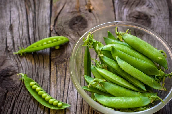 Gröna ärter i skål med ovanifrån på rustika trä bakgrund med c — Stockfoto