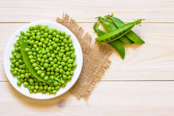 Ahşap arka plan, üstten görünüm veya düz beyaz kase yeşil bezelye 