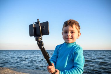 Genç çocuk bir selfie plajda, çocuk mutlu ve gülümseyerek tuvalet yapıyor