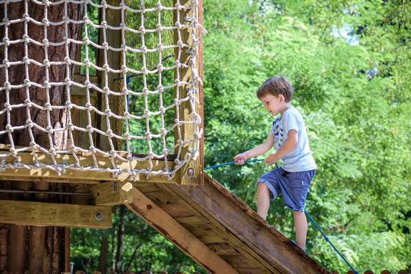 Little toddler boy kid having fun at a wooden playground outdoor