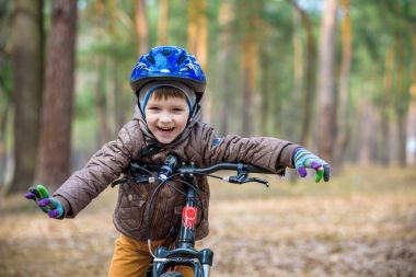 Güzel sonbahar gününde bir bisiklet ile sonbahar ormandaki eğleniyor 3 veya 5 yıllık mutlu bir çocukluk oğlan. Etkin alt giyen Bisiklet kask. Güvenlik, spor, eğlence çocuk kavramı ile.