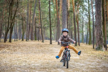 Güzel sonbahar gününde bir bisiklet ile sonbahar ormandaki eğleniyor 3 veya 5 yıllık mutlu bir çocukluk oğlan. Etkin alt giyen Bisiklet kask. Güvenlik, spor, eğlence çocuk kavramı ile.