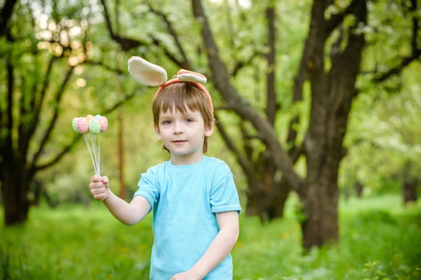 Kleiner Junge auf Ostereiersuche im Frühlingsgarten am Tag. Niedliches Kind mit traditionellem Hasen feiert Fest — Stockfoto