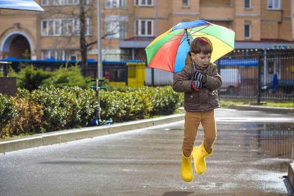 Mały chłopiec, grając w deszczowe lato park. Dziecko z kolorowe rai — Zdjęcie stockowe