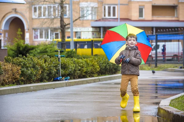 Mały chłopiec, grając w deszczowe lato park. Dziecko z kolorowe rai — Zdjęcie stockowe