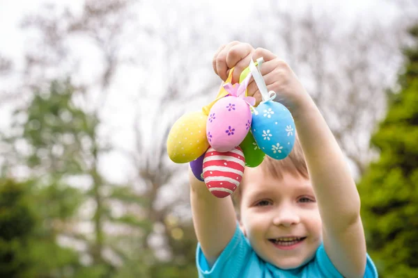 Huevos de Pascua de diferentes colores en las manos de un niño- caza de huevos —  Fotos de Stock