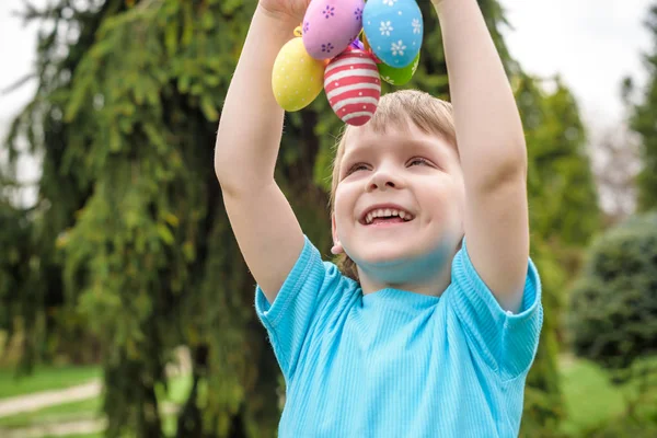Huevos de Pascua de diferentes colores en las manos de un niño- caza de huevos — Foto de Stock
