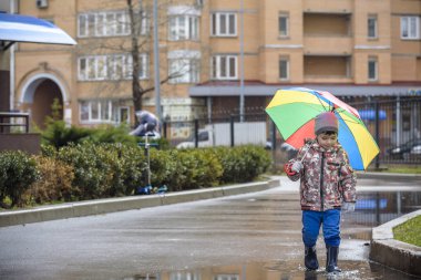 Yağmurlu yaz parkta oynarken küçük çocuk. Çocuk renkli rai ile