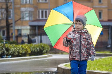 Yağmurlu yaz parkta oynarken küçük çocuk. Çocuk renkli rai ile