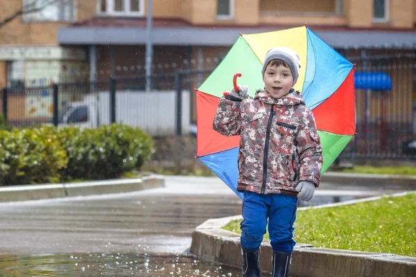 Mały chłopiec, grając w deszczowe lato park. Dziecko z kolorowe rai — Zdjęcie stockowe