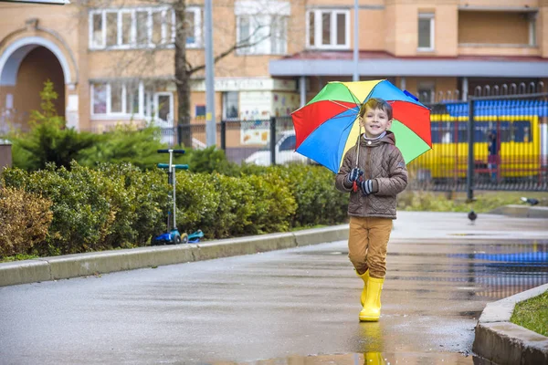 Mały chłopiec, grając w deszczowe lato park. Dziecko z kolorowe rai — Zdjęcie stockowe