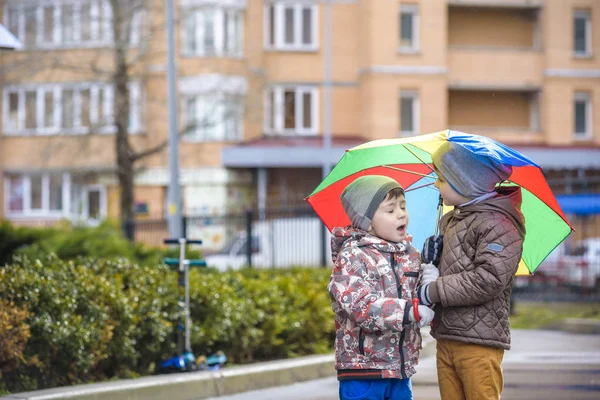 Dwóch małych chłopców, kucać na kałuży, z mało parasoli — Zdjęcie stockowe